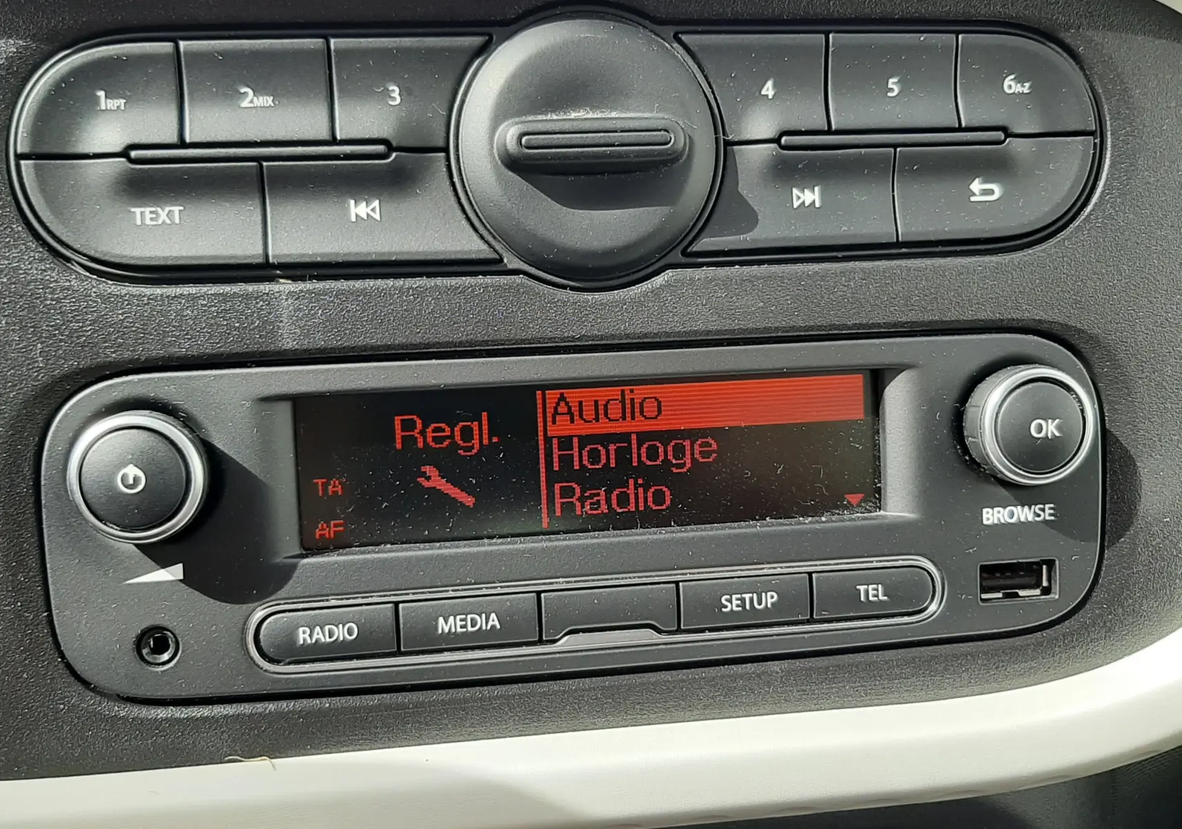 Détail du tableau de bord de la Renault Twingo III blanc cristal, avec l’écran radio affichant les réglages audio.