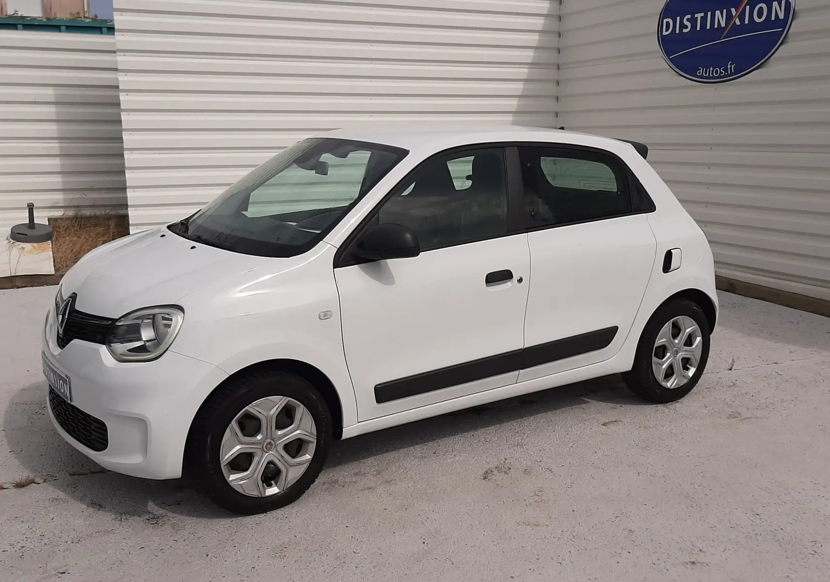 Renault Twingo III blanc cristal vue 3/4 avant droit, compacte cinq portes avec protections latérales noires.