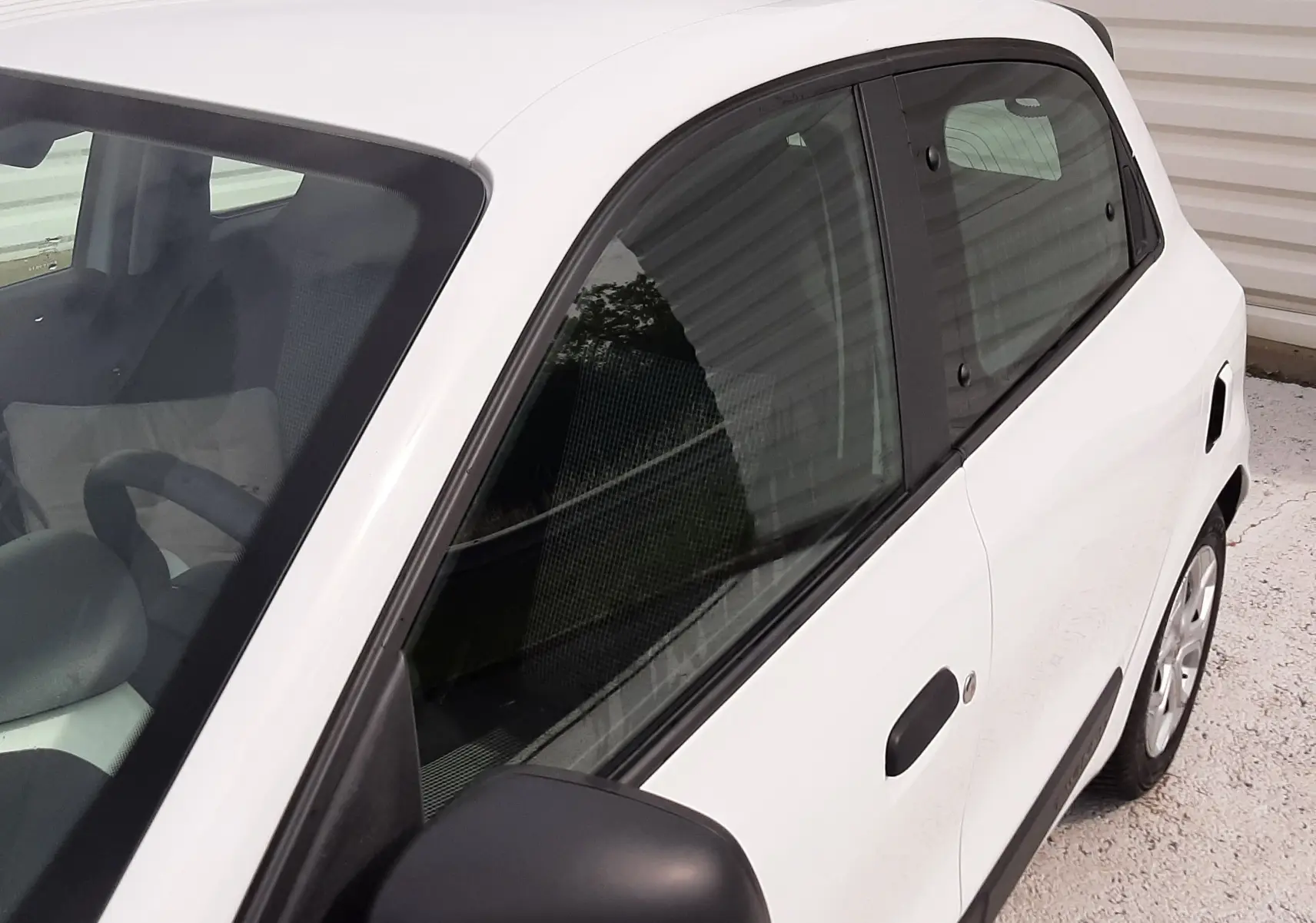 Vue de côté droit avant d'une Renault Twingo III blanc cristal, mettant en valeur les poignées noires et les vitres teintées.