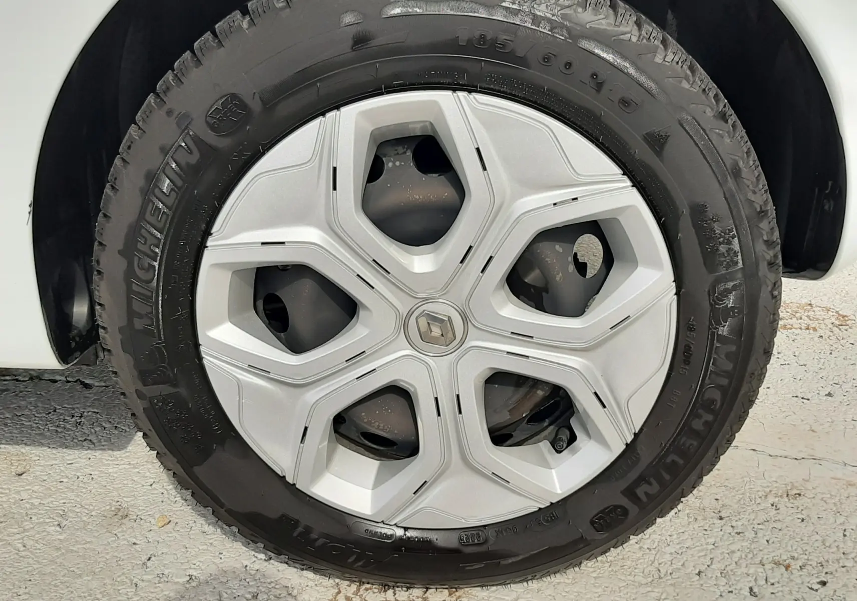 Gros plan sur la roue avant droite d'une Renault Twingo III blanche, mettant en valeur le pneu Michelin tout-terrain.