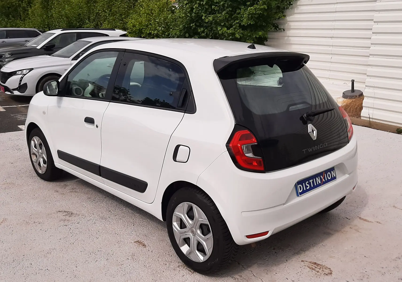 Vue 3/4 arrière droite d'une Renault Twingo III blanche cristal, avec vitres teintées et jantes alliage.