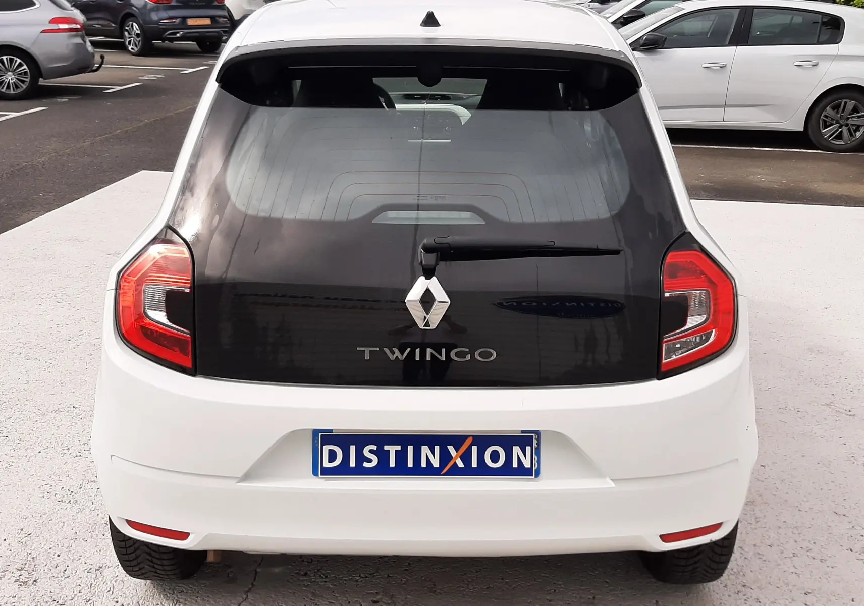 Vue arrière d'une Renault Twingo III blanc cristal avec lunette arrière noire et feux arrière distinctifs.
