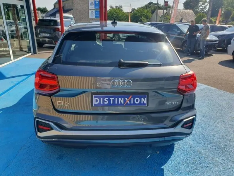 Vue arrière d'un Audi Q2 30 TDI gris Manhattan métallisé, avec feux LED et logo Distinxion visible.