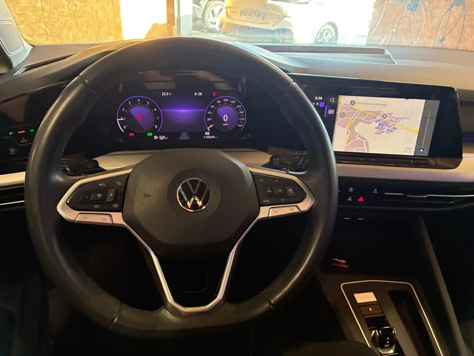 Vue intérieure centrée sur le volant Volkswagen d'une Golf 2023, avec tableau de bord numérique et écran tactile de navigation.