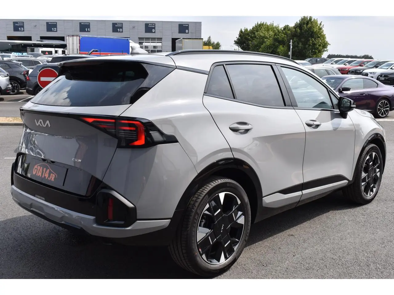 Vue 3/4 arrière droite du KIA Sportage hybride gris avec jantes noires et feux arrière LED distinctifs.