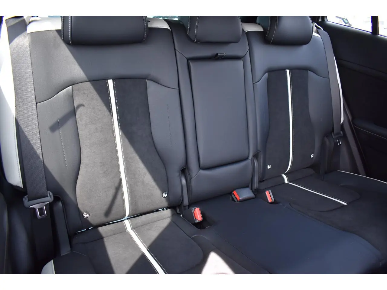 Vue rapprochée des sièges arrière bi-ton noir et gris du Kia Sportage hybride 2026 avec ceintures visibles.