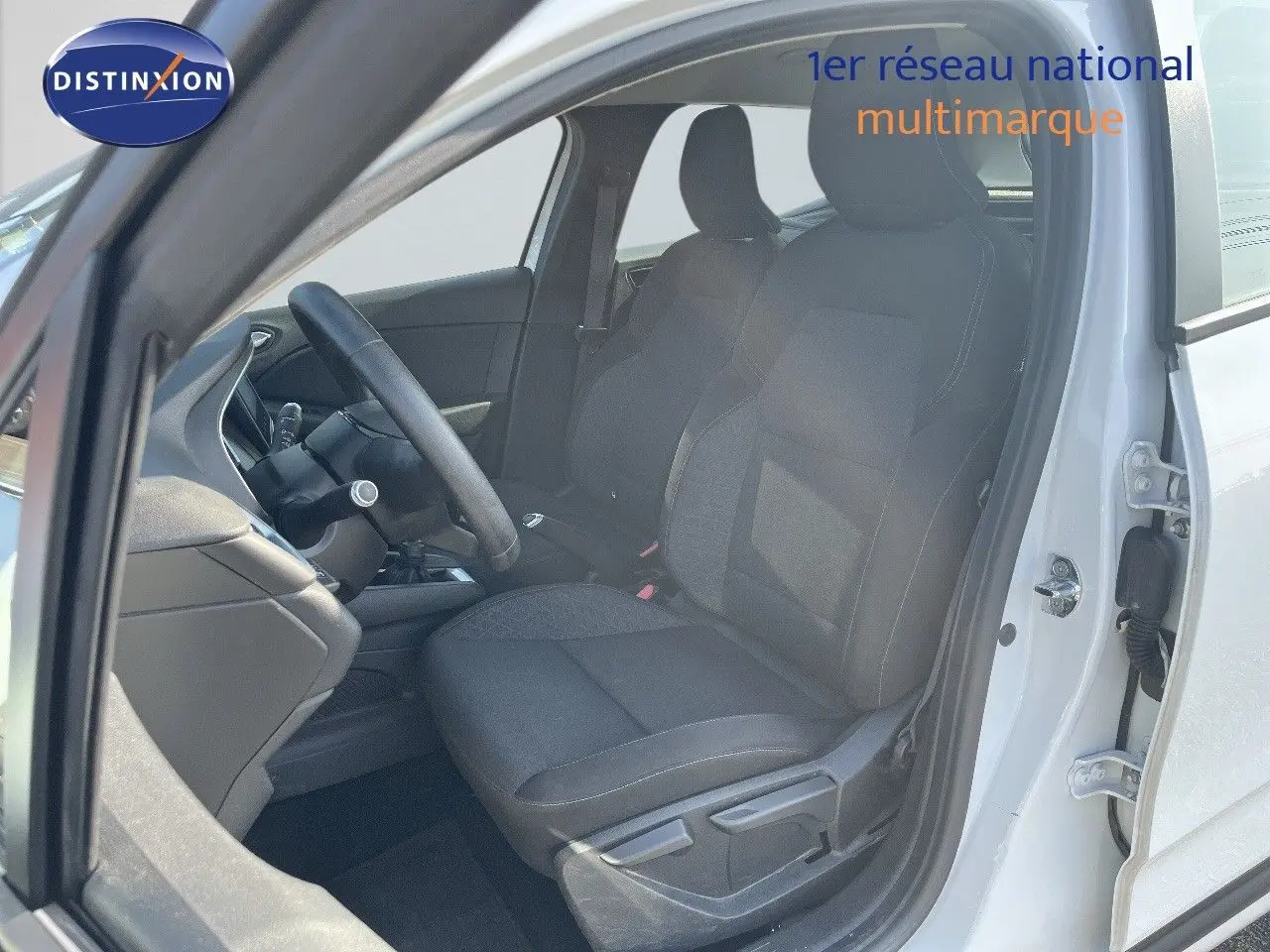 Intérieur côté conducteur d'une Renault Clio Société blanc glacier, sièges tissu gris noir et volant multifonction visible.