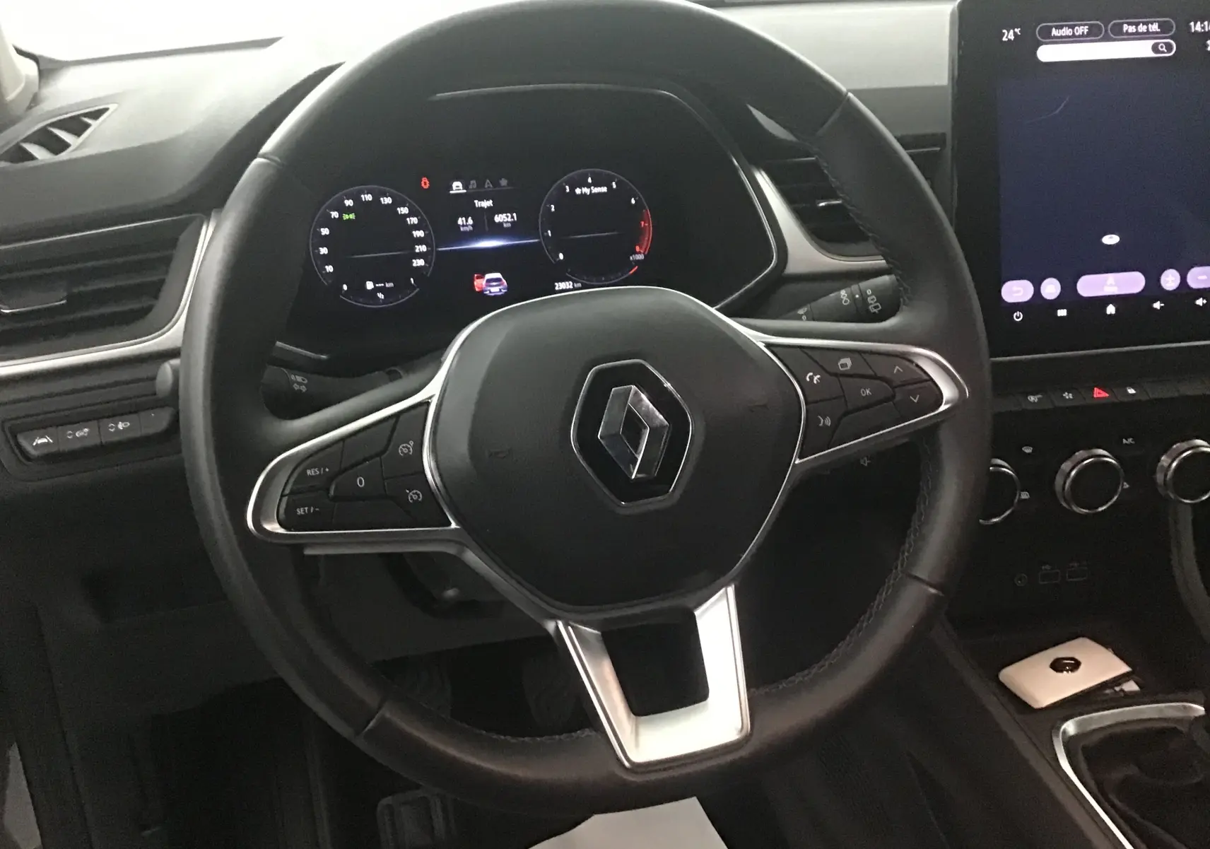 Vue rapprochée du volant noir du Renault Captur 2024 avec tableau de bord digital et écran tactile central allumé.
