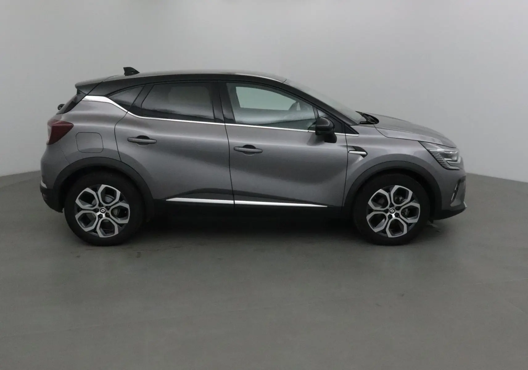 Profil droit du Renault Captur 2024 gris Cassiopée avec toit noir et lignes chromées élégantes.