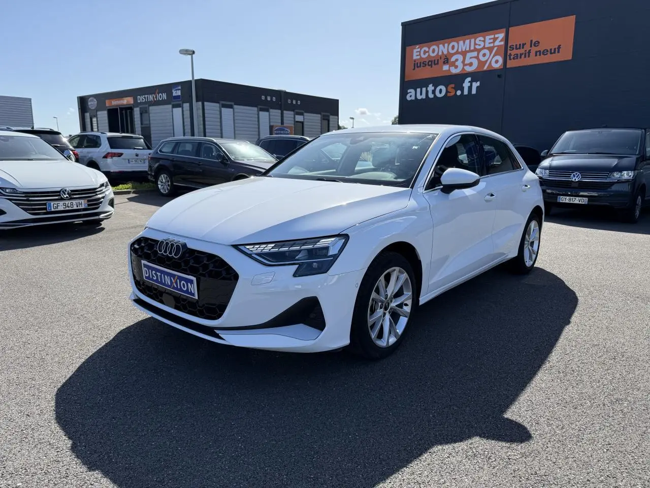 Audi A3 Sportback blanc Arcona vue 3/4 avant droit avec jantes alliage 5 branches sur parking extérieur.