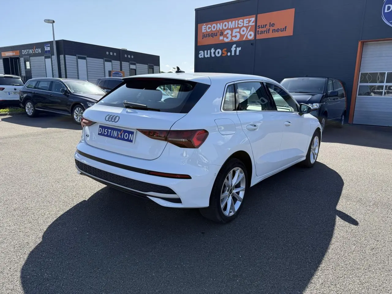 Audi A3 Sportback blanc Arcona vue 3/4 arrière droit sur parking avec jantes alliage 17 pouces et feux arrière LED.