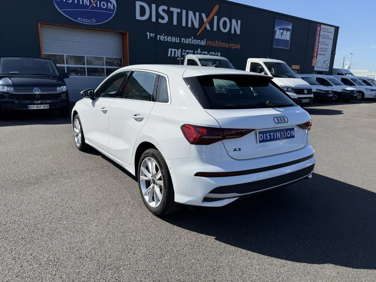 Audi A3 Sportback blanc Arcona vue 3/4 arrière droit, jantes alliage 5 branches et feux arrière LED visibles.