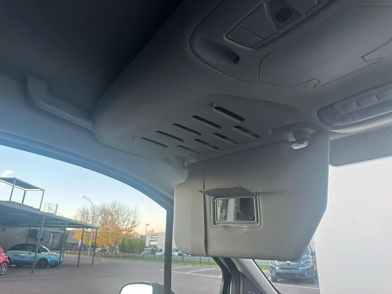 Vue intérieure côté conducteur du pare-soleil avec miroir intégré du Ford Transit Connect blanc stationné à l'extérieur.