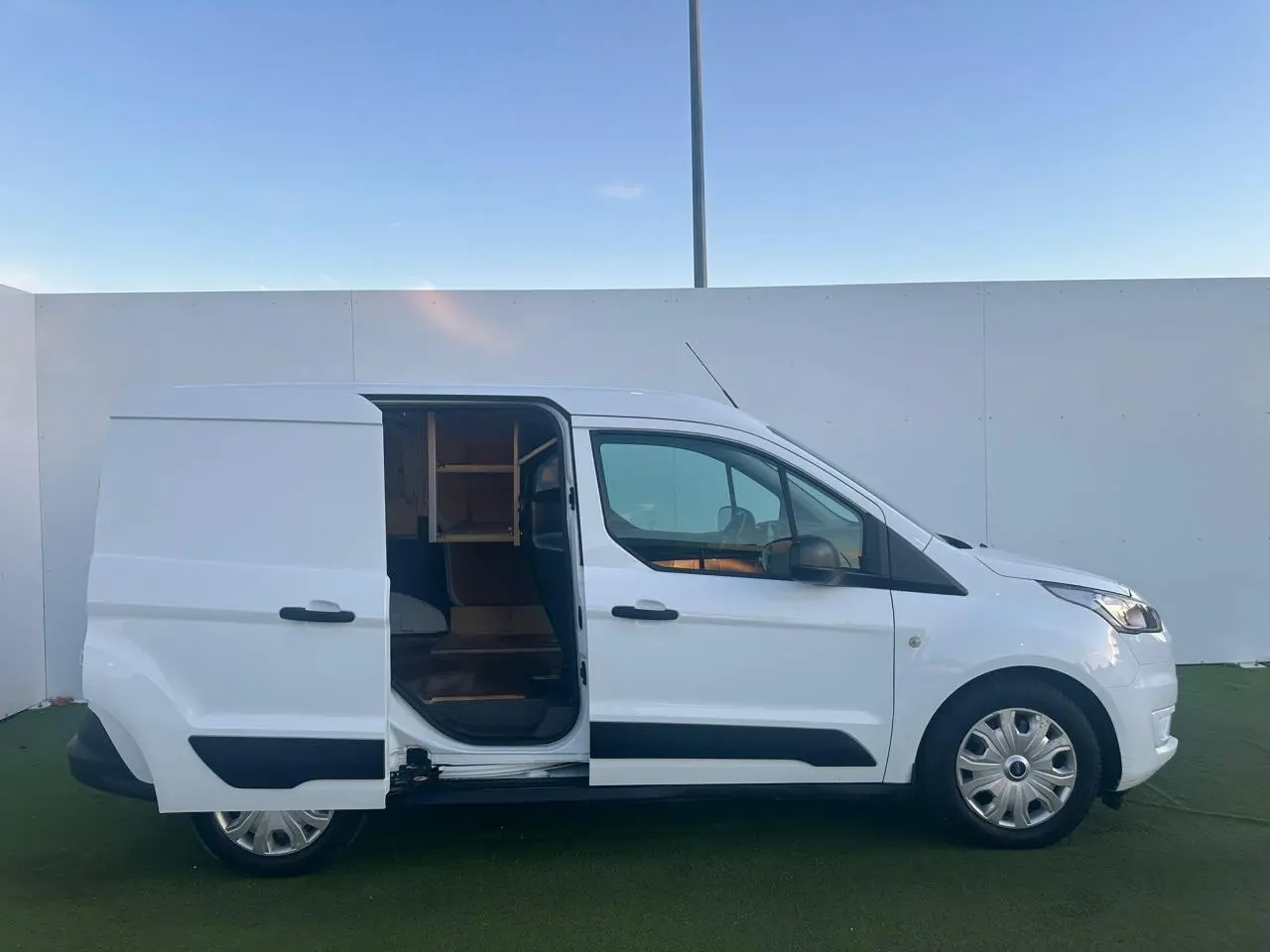 Vue latérale droite d'un Ford Transit Connect blanc 2019 avec porte coulissante ouverte et jantes acier.