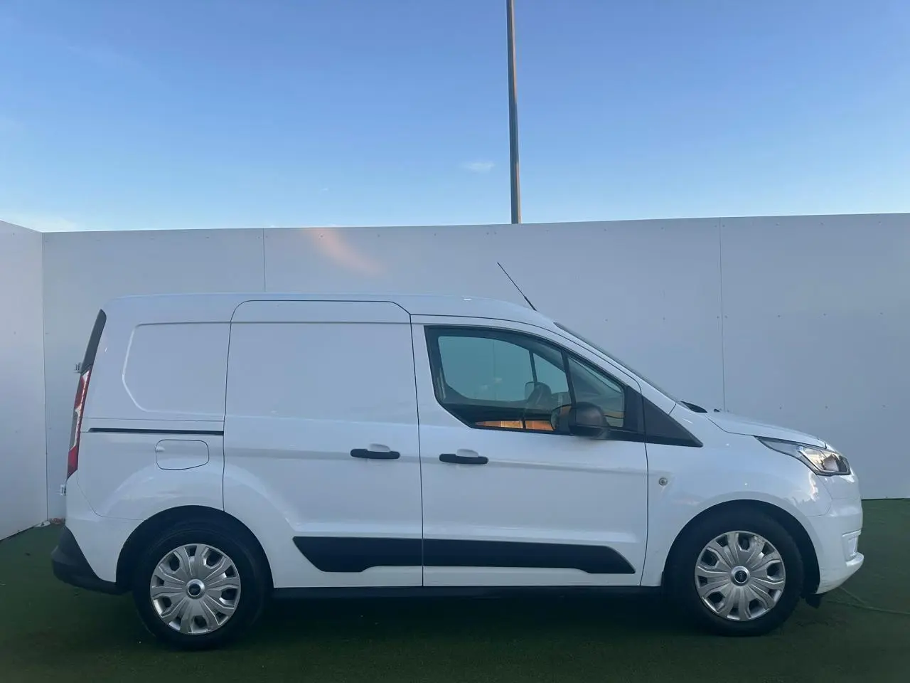 Profil droit d'un fourgon blanc Ford Transit Connect 2019 avec porte latérale coulissante et protections noires.