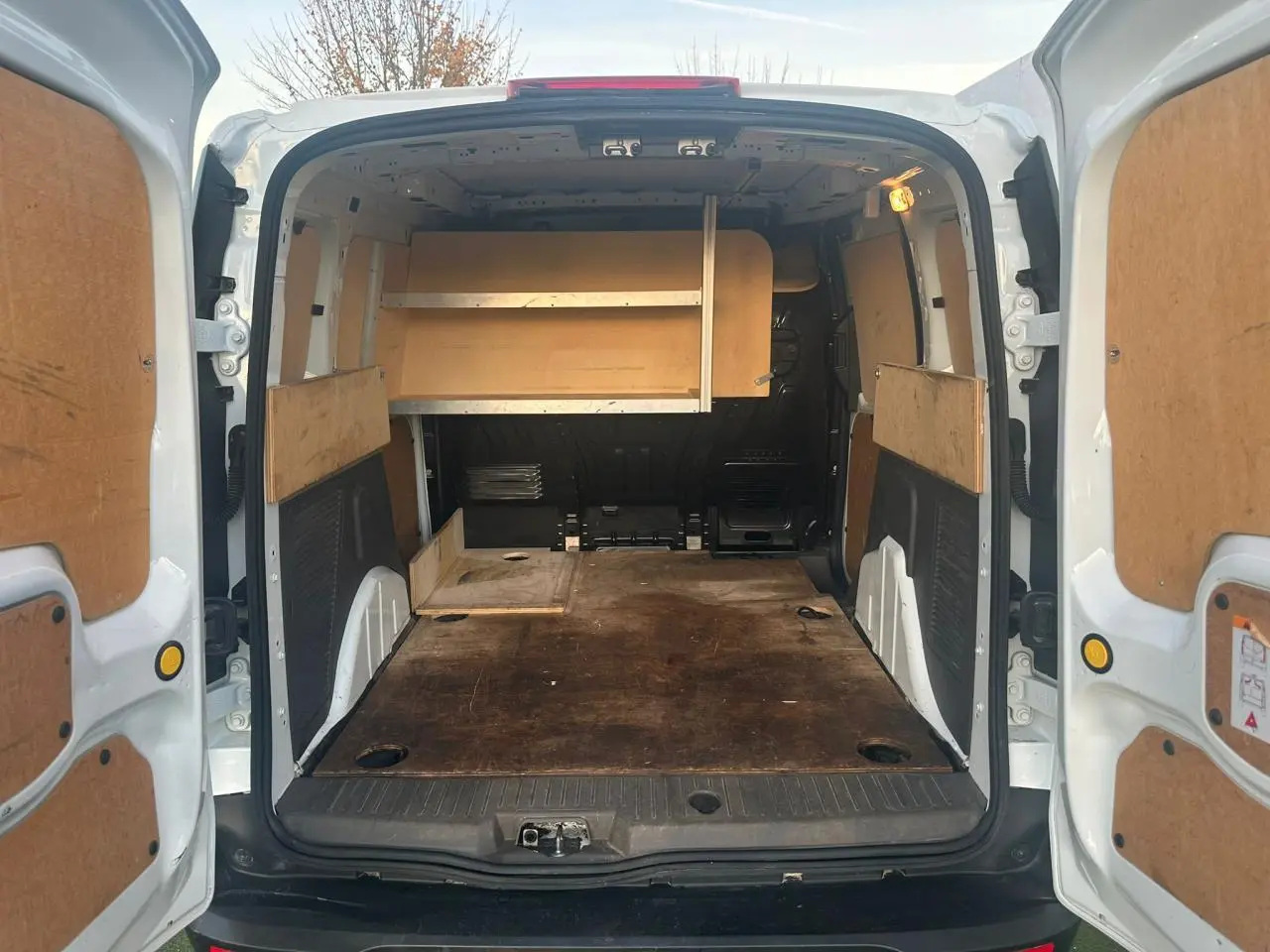 Vue arrière du fourgon blanc Ford Transit Connect 2019 avec portes ouvertes et espace de chargement en bois aménagé.