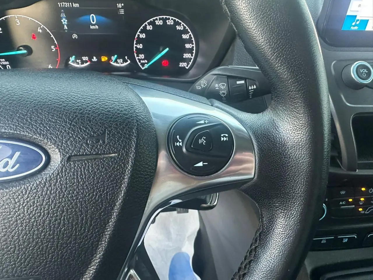 Gros plan sur le volant multifonction noir et le tableau de bord numérique du Ford Transit Connect blanc de 2019.