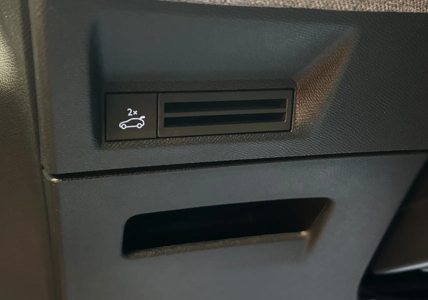 Gros plan sur le bouton d'ouverture du hayon dans l'habitacle noir du Peugeot 3008 III Hybrid 2025.