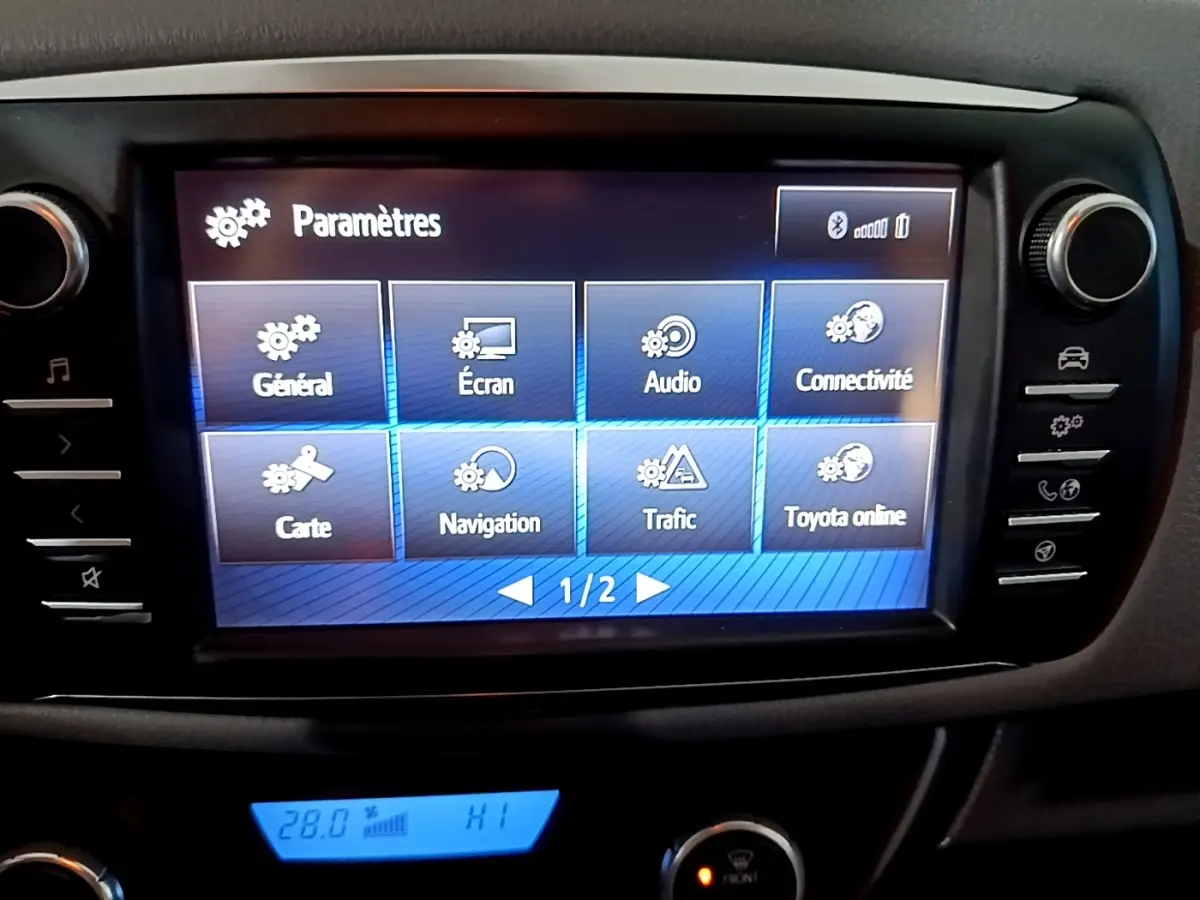 Écran tactile central en mode paramètres dans l'habitacle d'une Toyota Yaris blanche, vue de face rapprochée.
