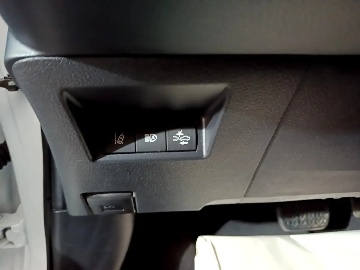 Gros plan sur les boutons de commande sous le tableau de bord d'une Toyota Yaris blanche, côté conducteur.