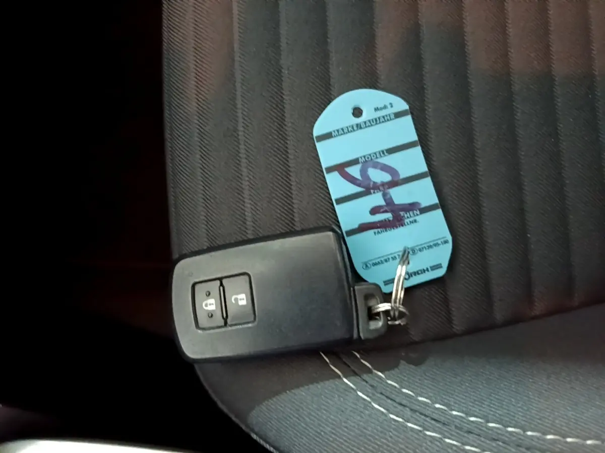 Télécommande noire de démarrage sans clé posée sur un siège tissu gris foncé à surpiqûres blanches, intérieur Toyota Yaris 2020.