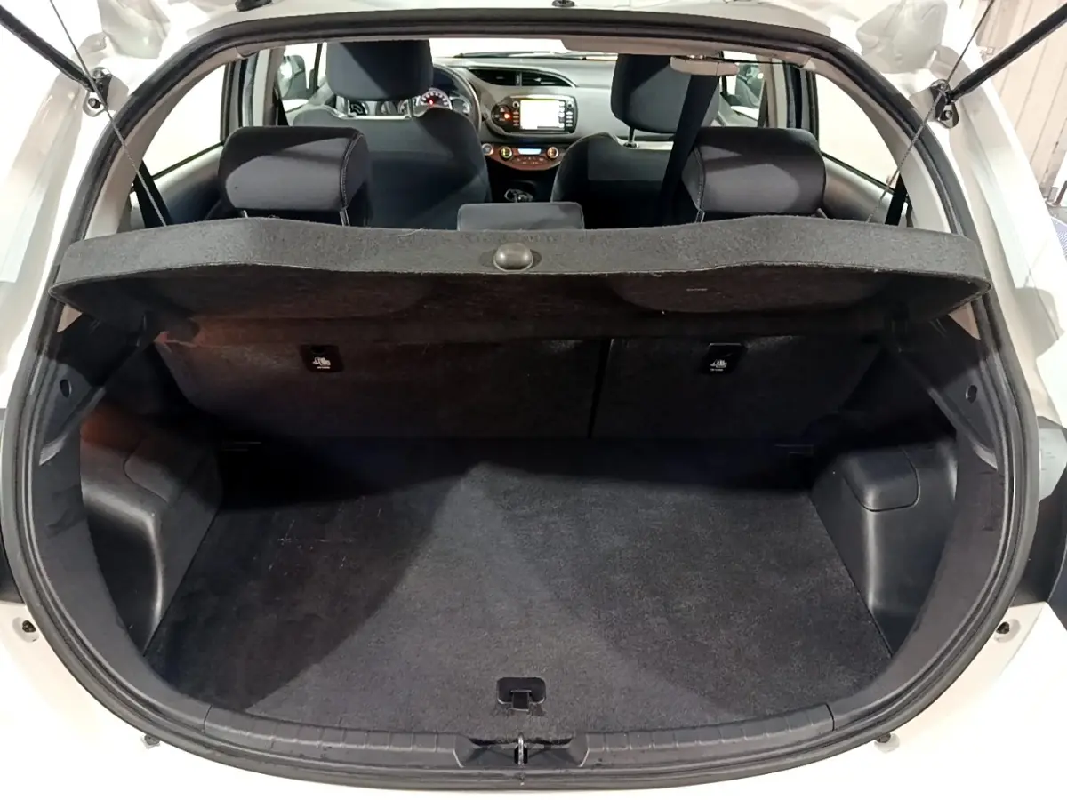 Coffre ouvert d’une Toyota Yaris blanche 2020, vue arrière, banquette arrière et tableau de bord visibles.