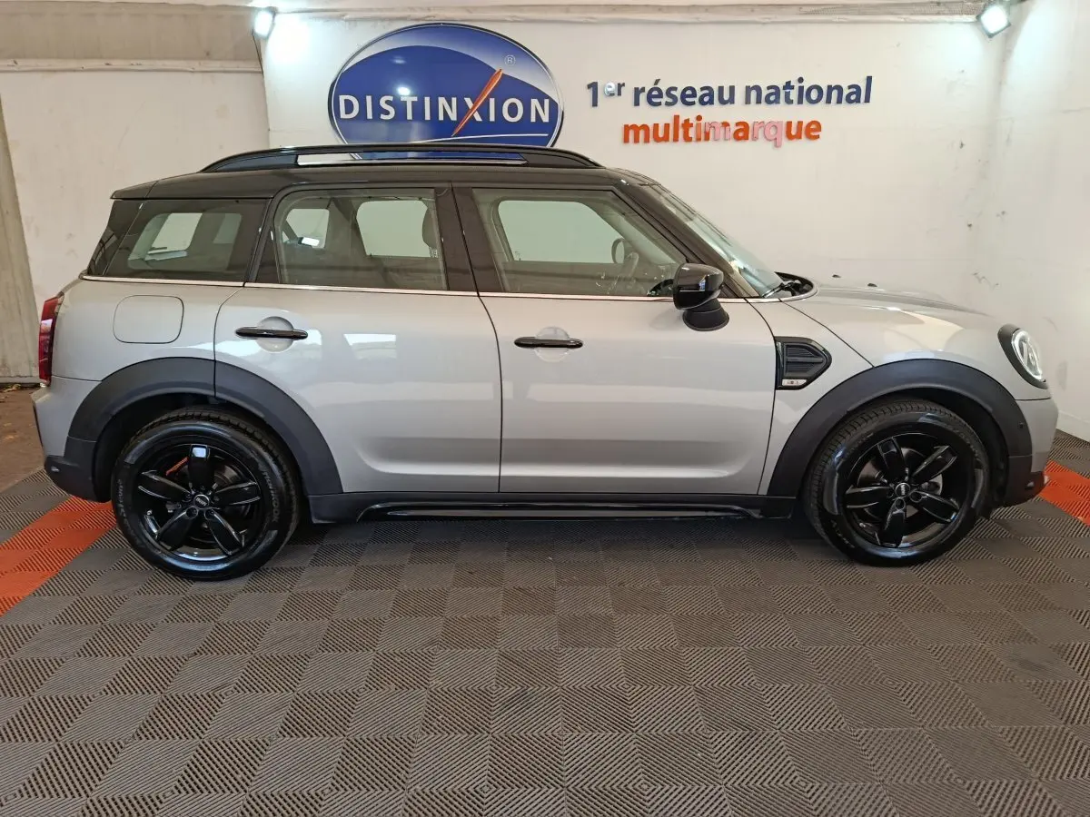 Vue de profil droit d'un MINI Countryman gris foncé avec toit noir et jantes noires brillantes dans un showroom.