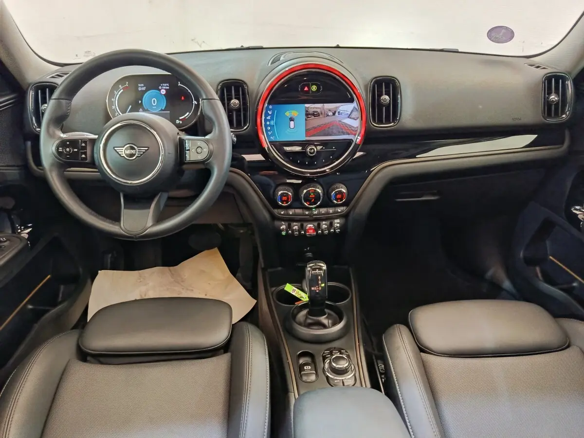 Vue intérieure avant du tableau de bord et volant cuir noir du MINI Countryman Cooper 2023 avec écran tactile central lumineux.