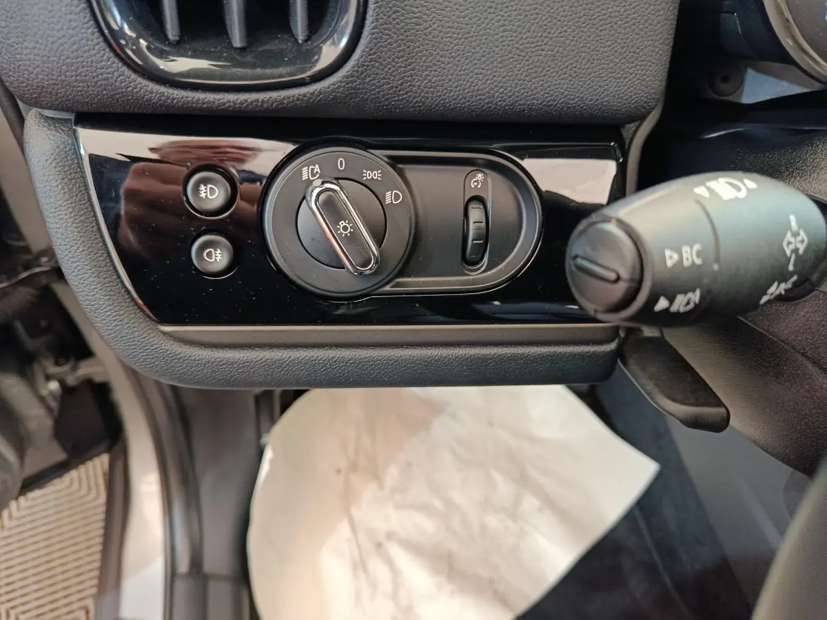 Gros plan sur la commande des phares et clignotants côté gauche du tableau de bord du MINI Countryman gris foncé 2023.