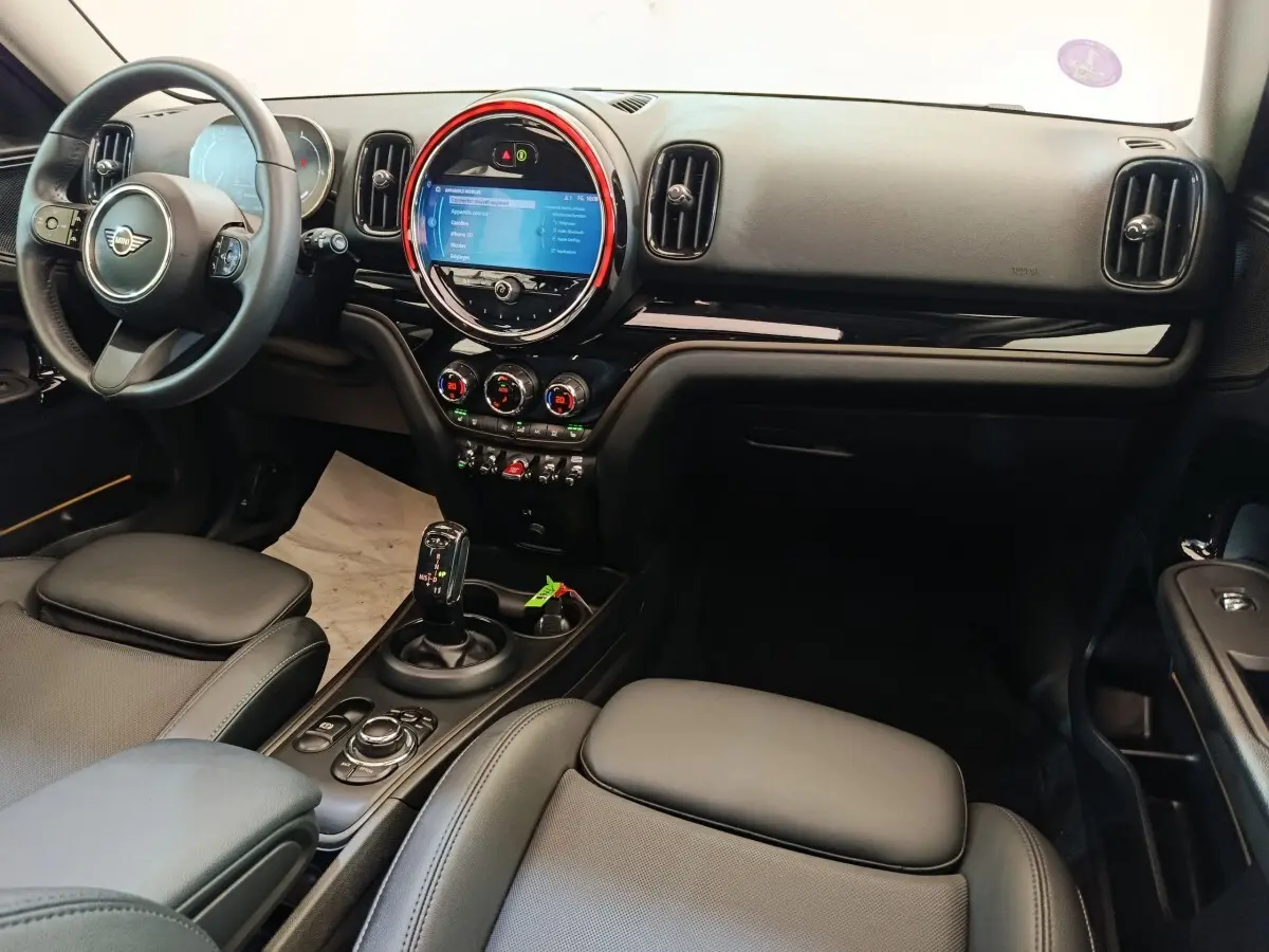 Vue intérieure avant droite du tableau de bord noir et écran tactile circulaire avec éclairage rouge du MINI Countryman 2023.