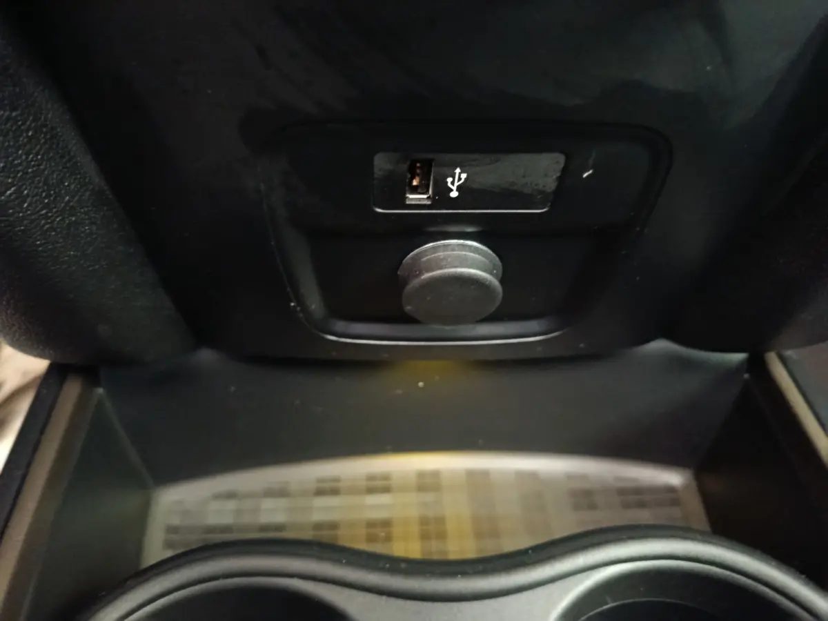 Gros plan sur la prise USB et la prise 12V dans le compartiment central d’un MINI Countryman gris foncé.
