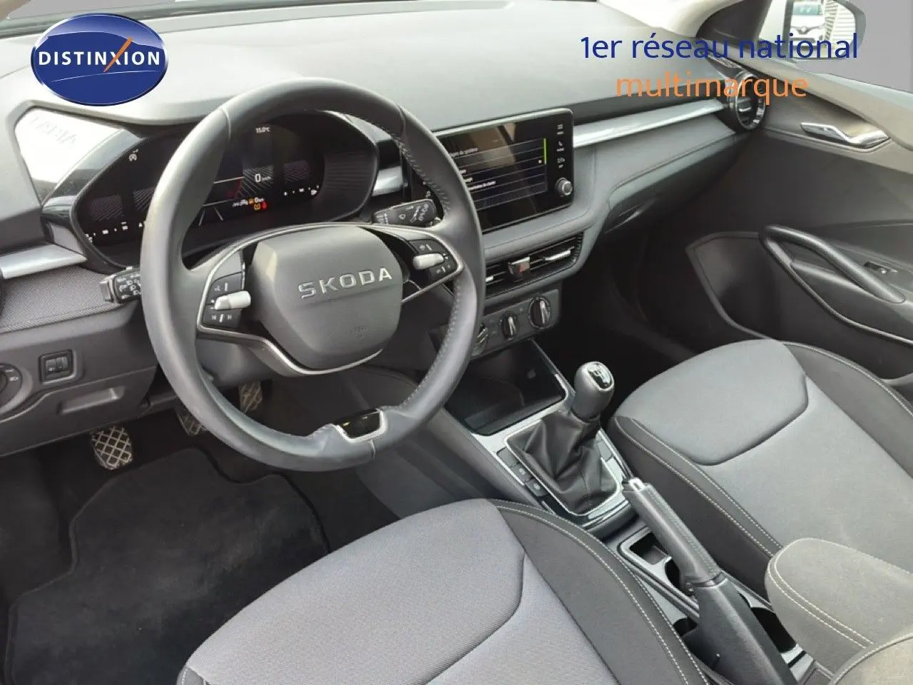 Vue intérieure côté conducteur de la Skoda Fabia 2025, tableau de bord moderne avec volant multifonction et écran tactile central.