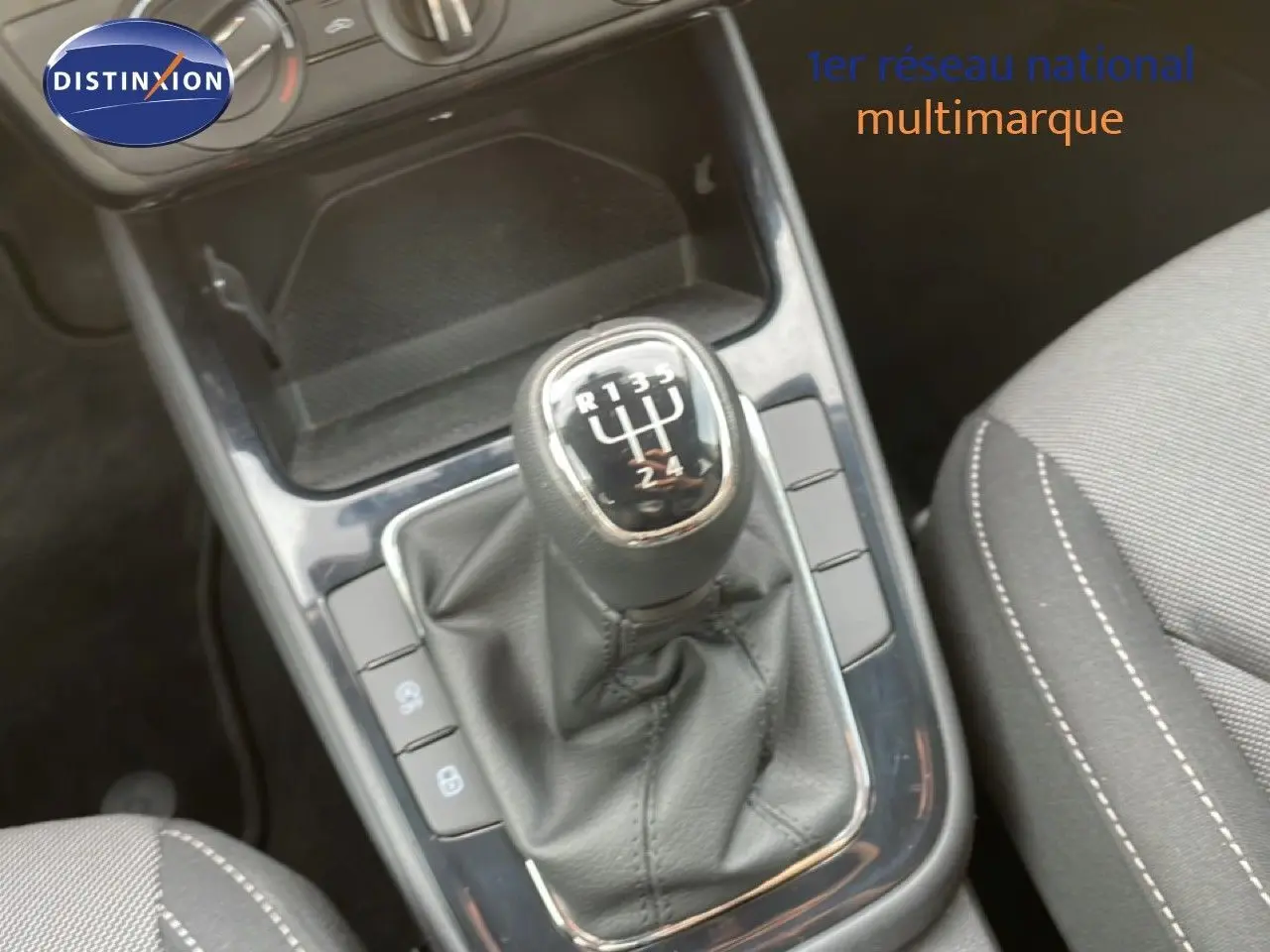 Gros plan sur le levier de vitesse manuel en cuir noir de la Skoda Fabia blanc glacier, avec console centrale et siège tissu gris.