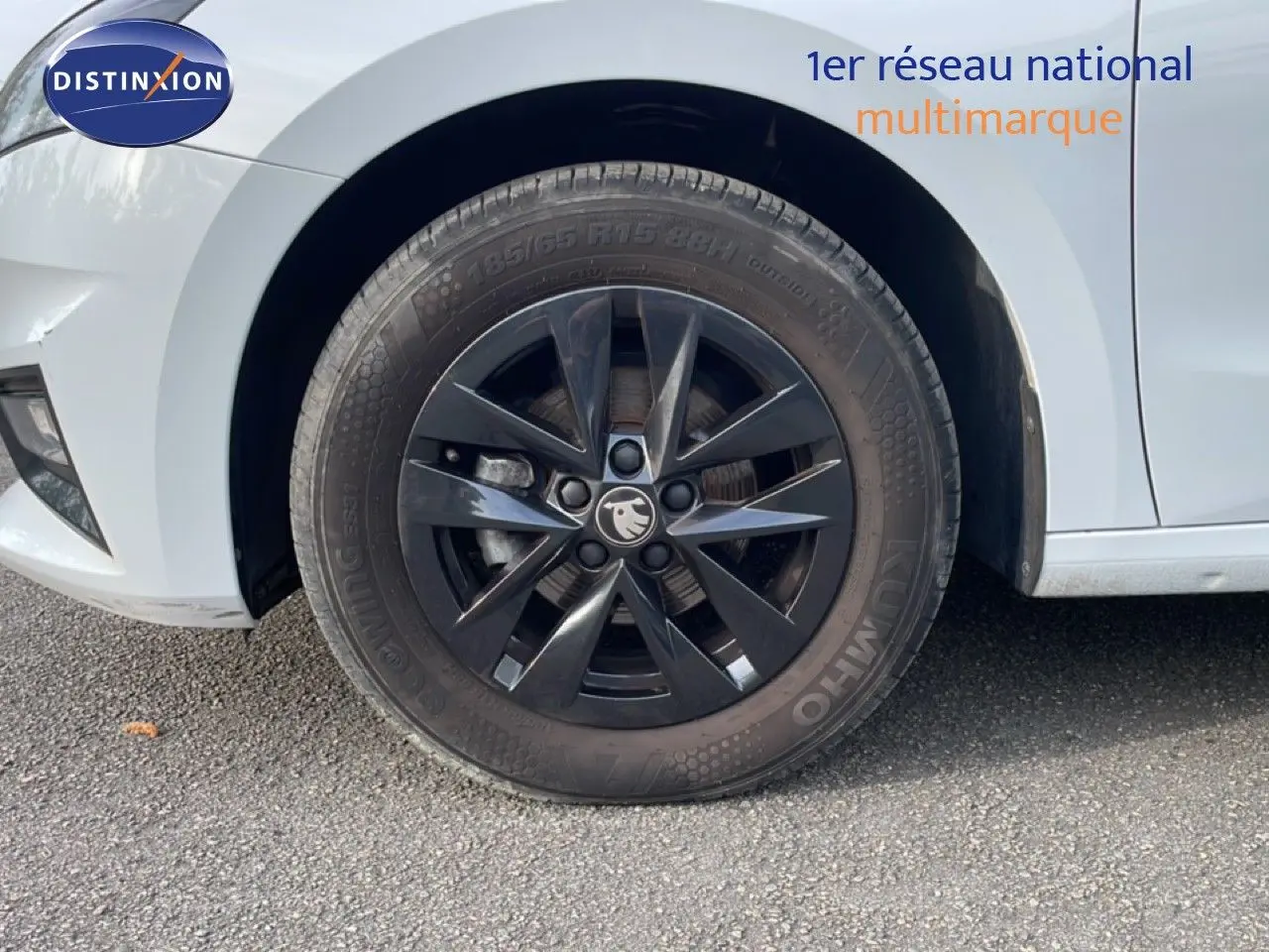 Gros plan sur la roue avant gauche noire d’une Skoda Fabia blanc glacier, soulignant la jante au design moderne.