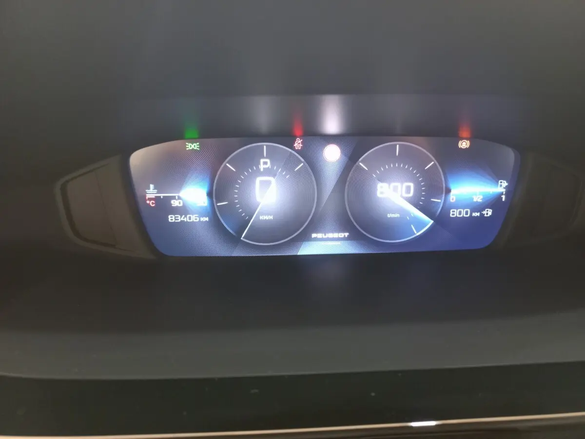 Tableau de bord numérique de Peugeot 308 bleu, affichant vitesse, compte-tours et jauges, vue frontale rapprochée.