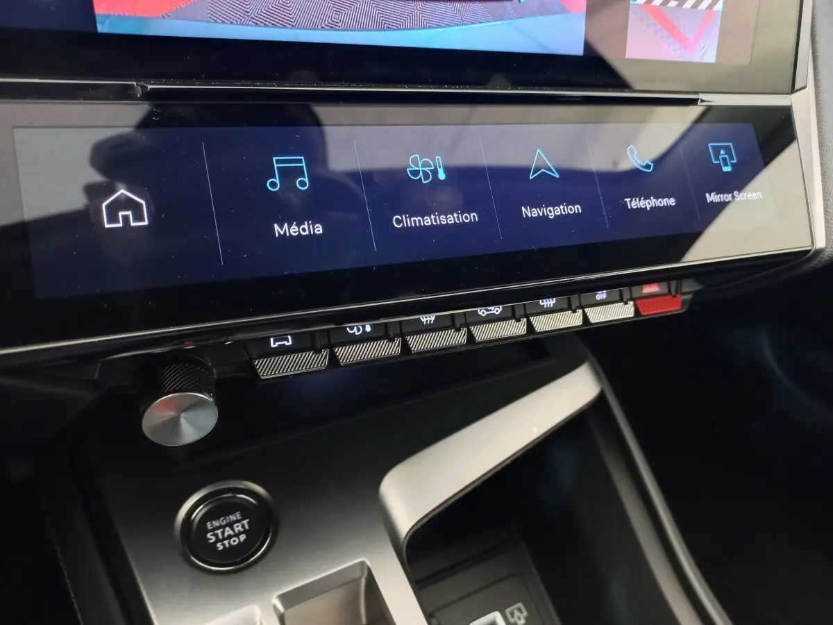 Vue rapprochée de la console centrale de la Peugeot 308 2022, écran tactile avec options média, navigation et bouton start/stop.