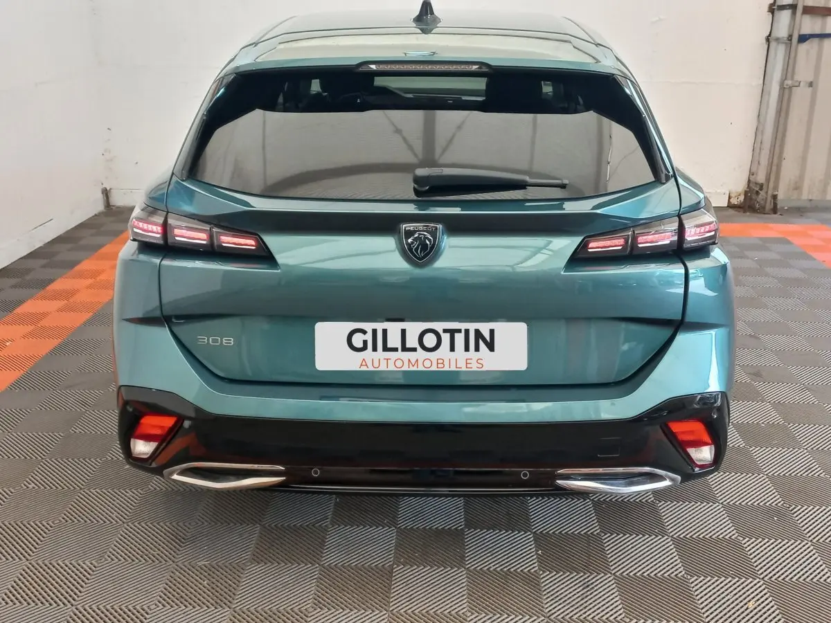 Vue arrière d'une Peugeot 308 bleu métallisé 2022 avec feux LED et double sortie d'échappement chromée.