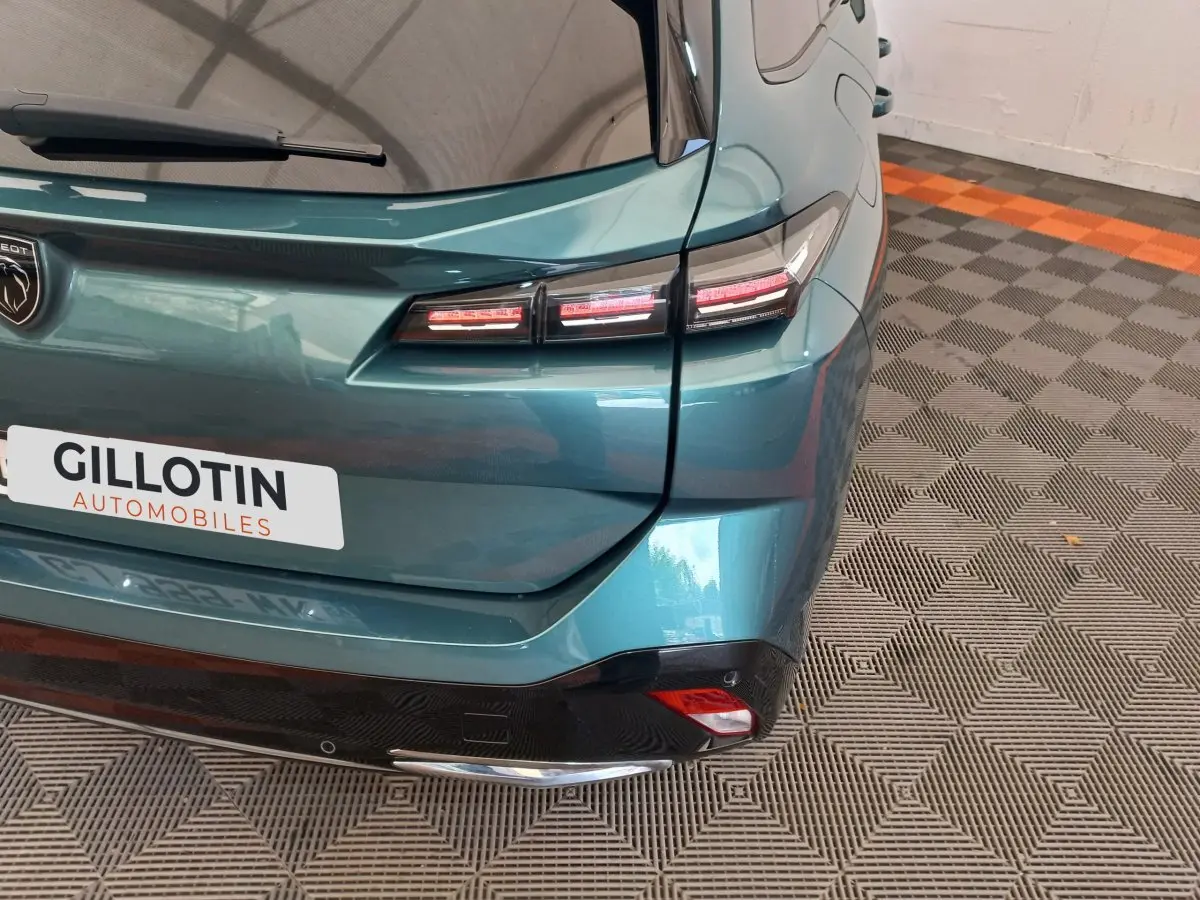 Vue arrière droite d'une Peugeot 308 bleu métallisé avec feux arrière LED et logo Peugeot visible.