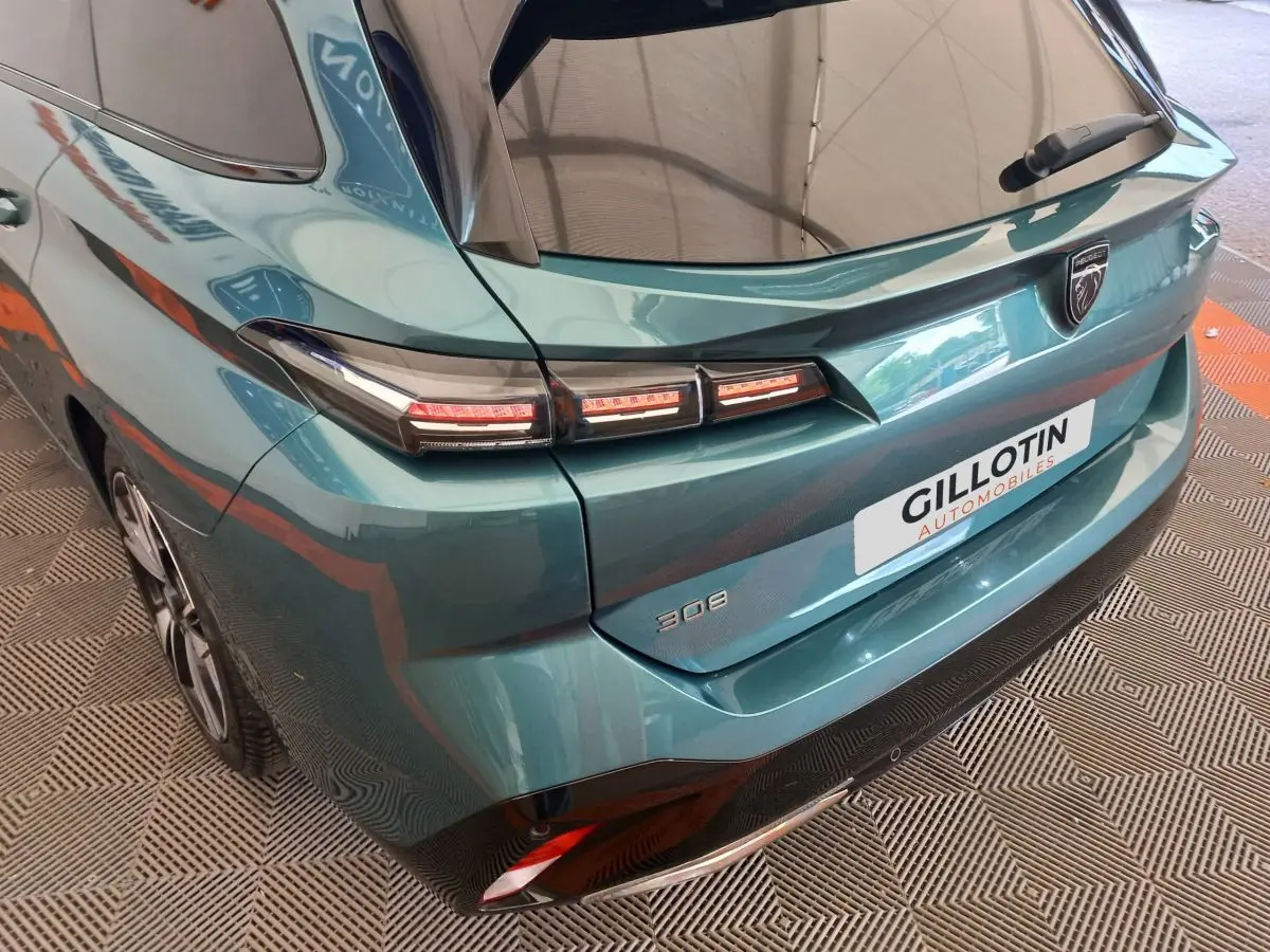 Vue 3/4 arrière droite d'une Peugeot 308 bleu avec feux arrière LED et logo Peugeot visible sur le hayon.