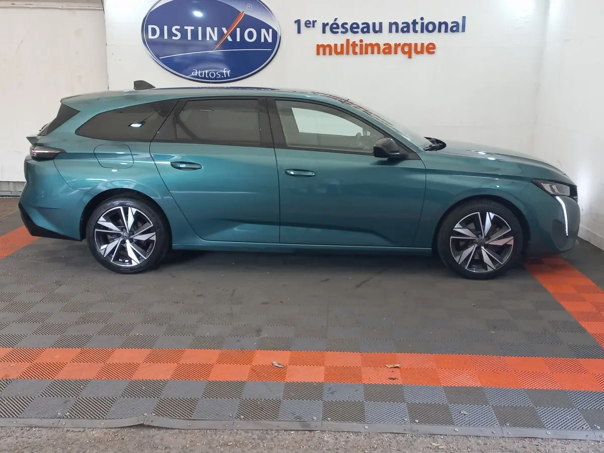 Vue de profil côté gauche d'une Peugeot 308 break bleu métallisé, avec jantes alliage et vitres teintées.