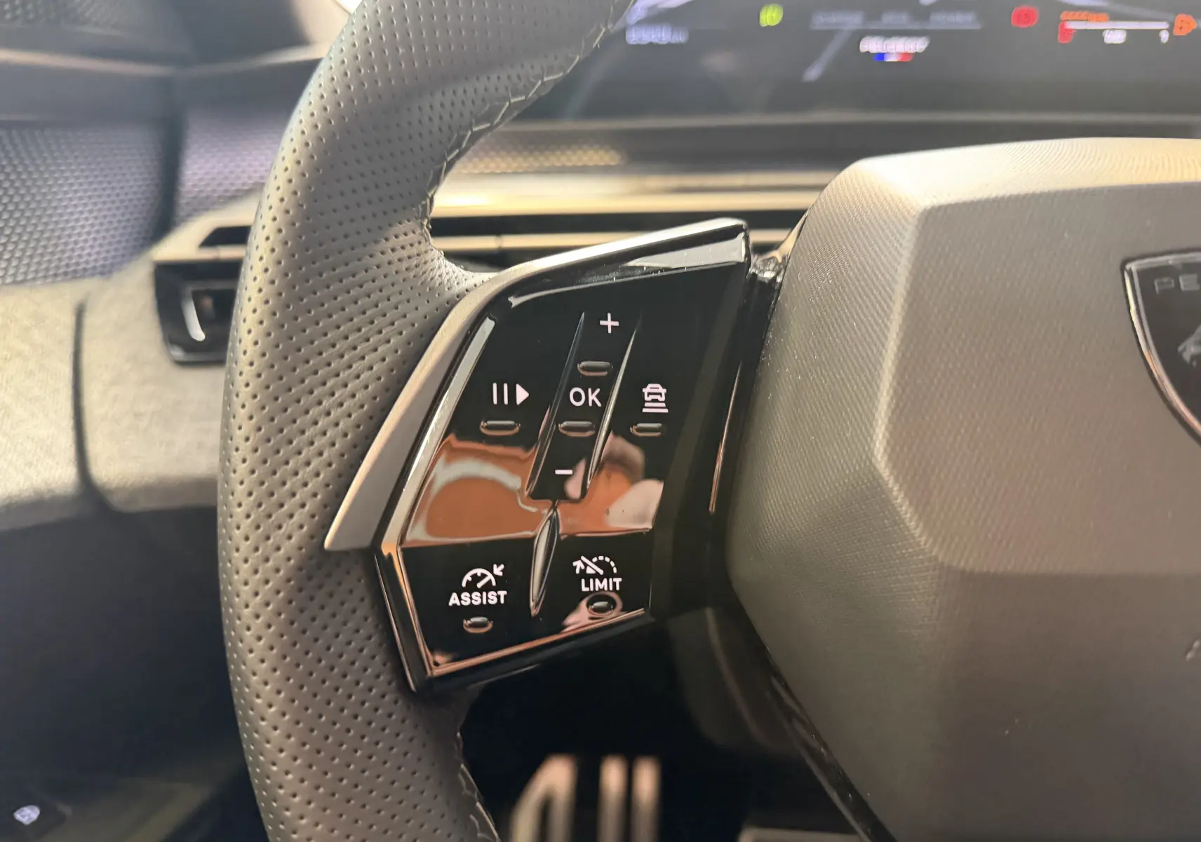 Gros plan sur le côté gauche du volant perforé du Peugeot 3008 Hybrid 145 GT avec commandes intégrées et finition noire.