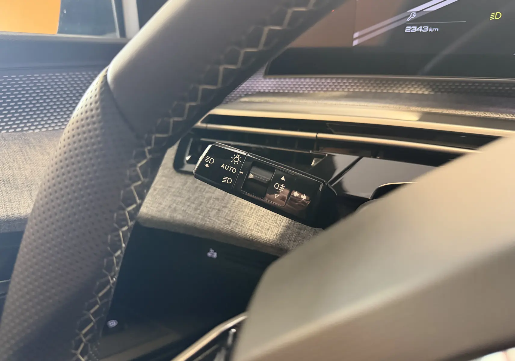 Gros plan sur la commande des feux et clignotants à gauche du volant dans l’habitacle du Peugeot 3008 Hybrid 2025.