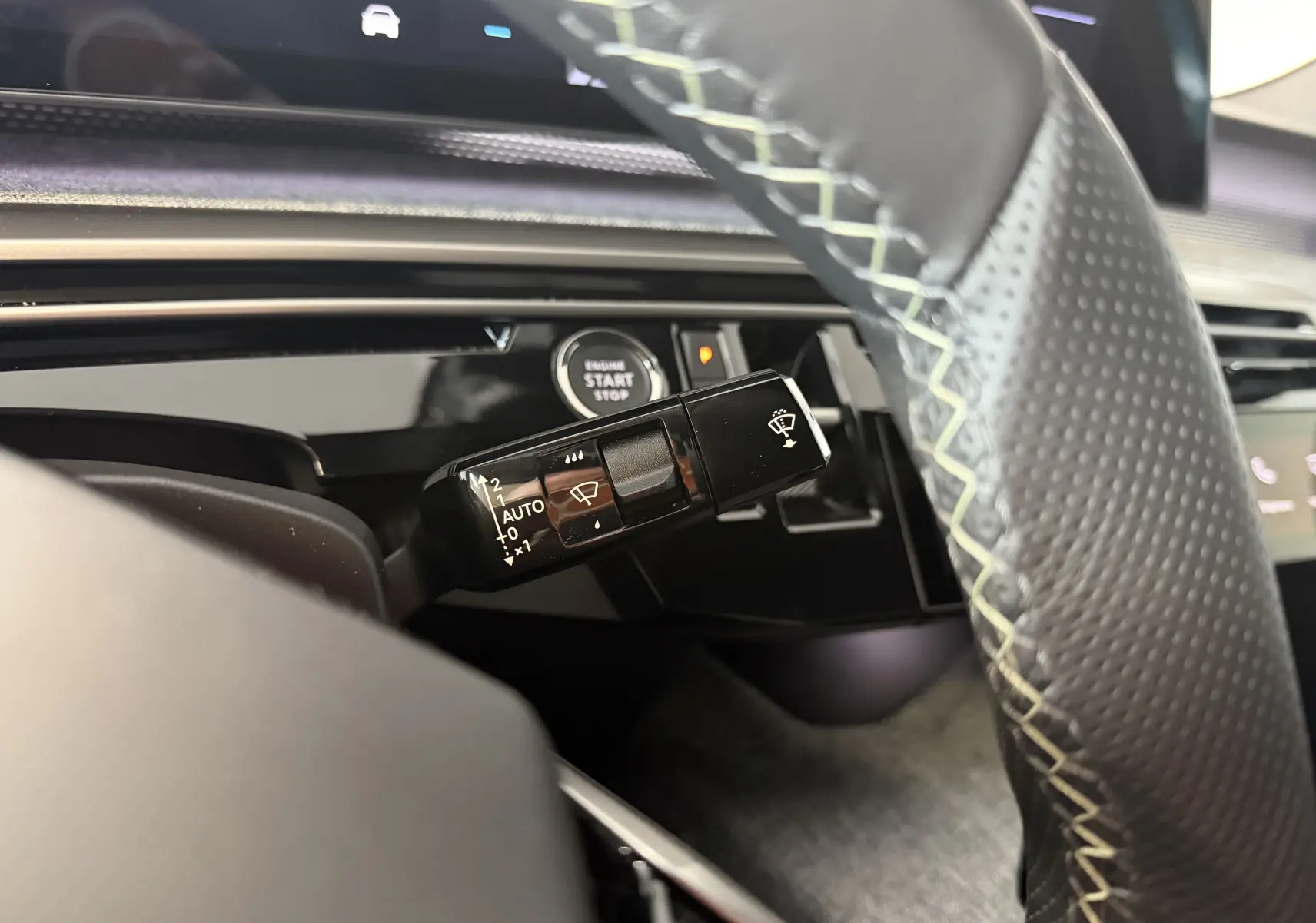 Gros plan sur la commande d’essuie-glace à gauche du volant perforé dans l’habitacle du Peugeot 3008 Hybrid 145 GT 2025.