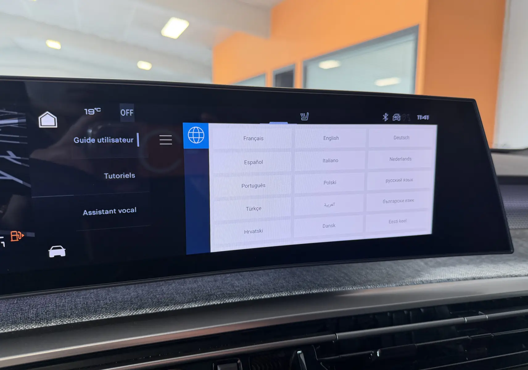 Écran tactile intérieur du Peugeot 3008 Hybrid 145 GT affichant le menu de sélection des langues, avec tableau de bord en tissu gris.