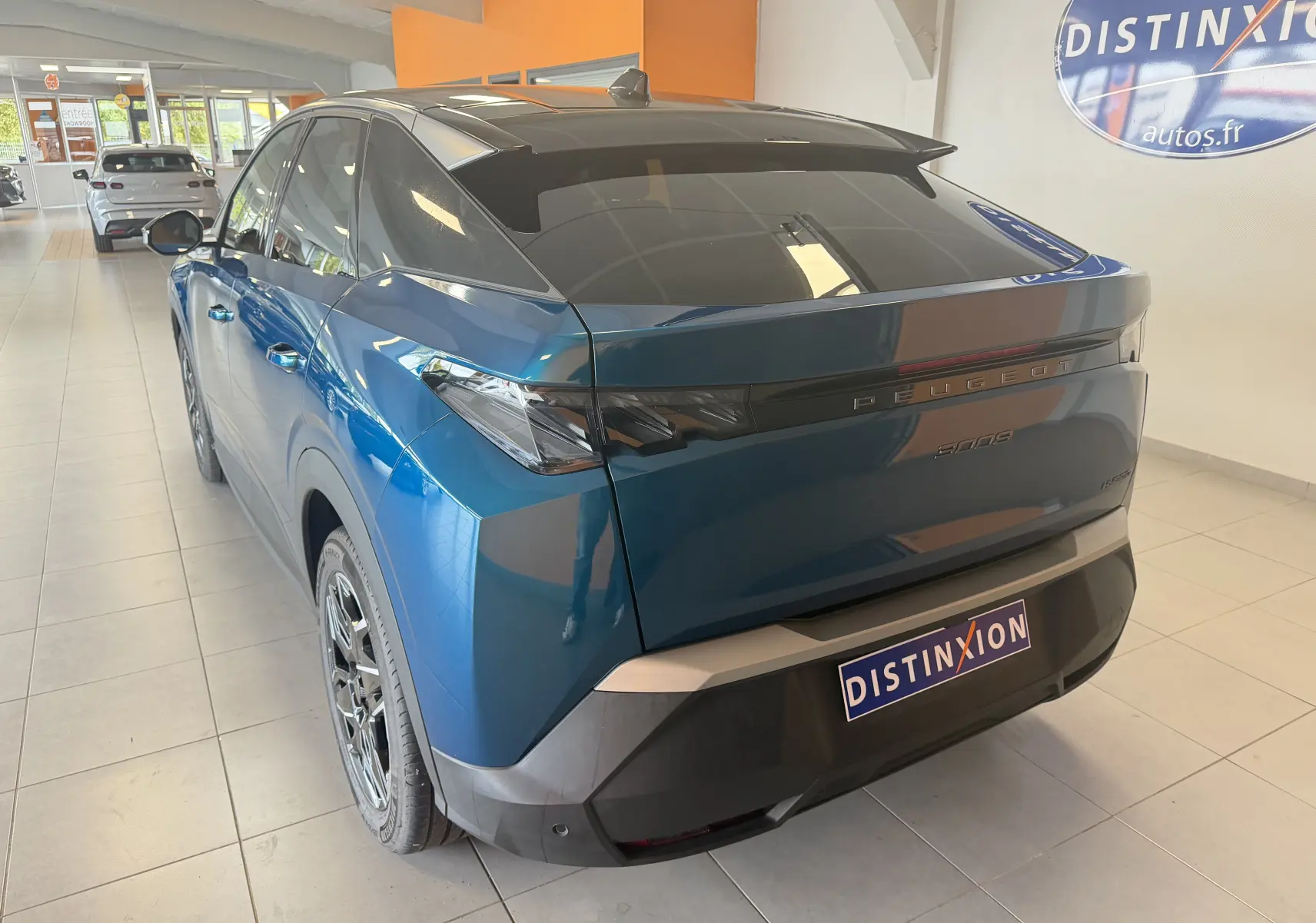 Vue 3/4 arrière droite du Peugeot 3008 Hybrid 145 GT bleu Obsession avec toit noir et jantes alliage 19 pouces en showroom.