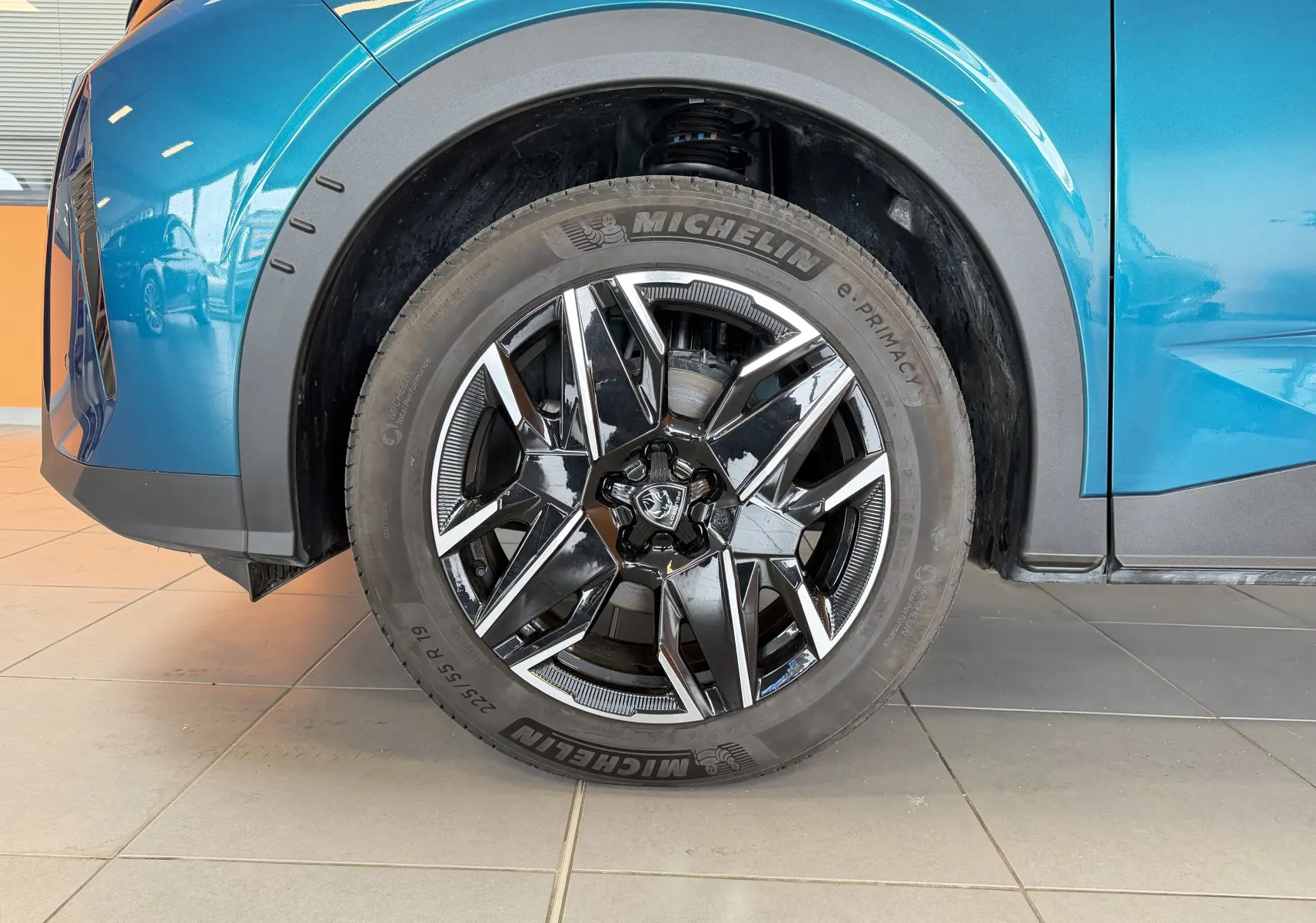 Gros plan sur la roue avant droite du Peugeot 3008 Hybrid 145 GT bleu Obsession avec jante alliage 19 pouces bicolore.