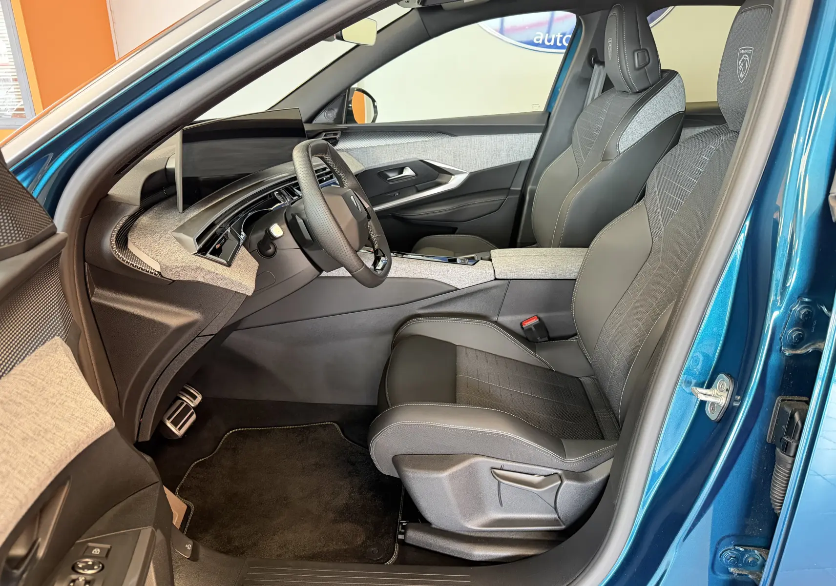 Vue intérieure côté conducteur du Peugeot 3008 Hybrid 145 GT bleu obsession, avec sellerie tissu gris et détails modernes.