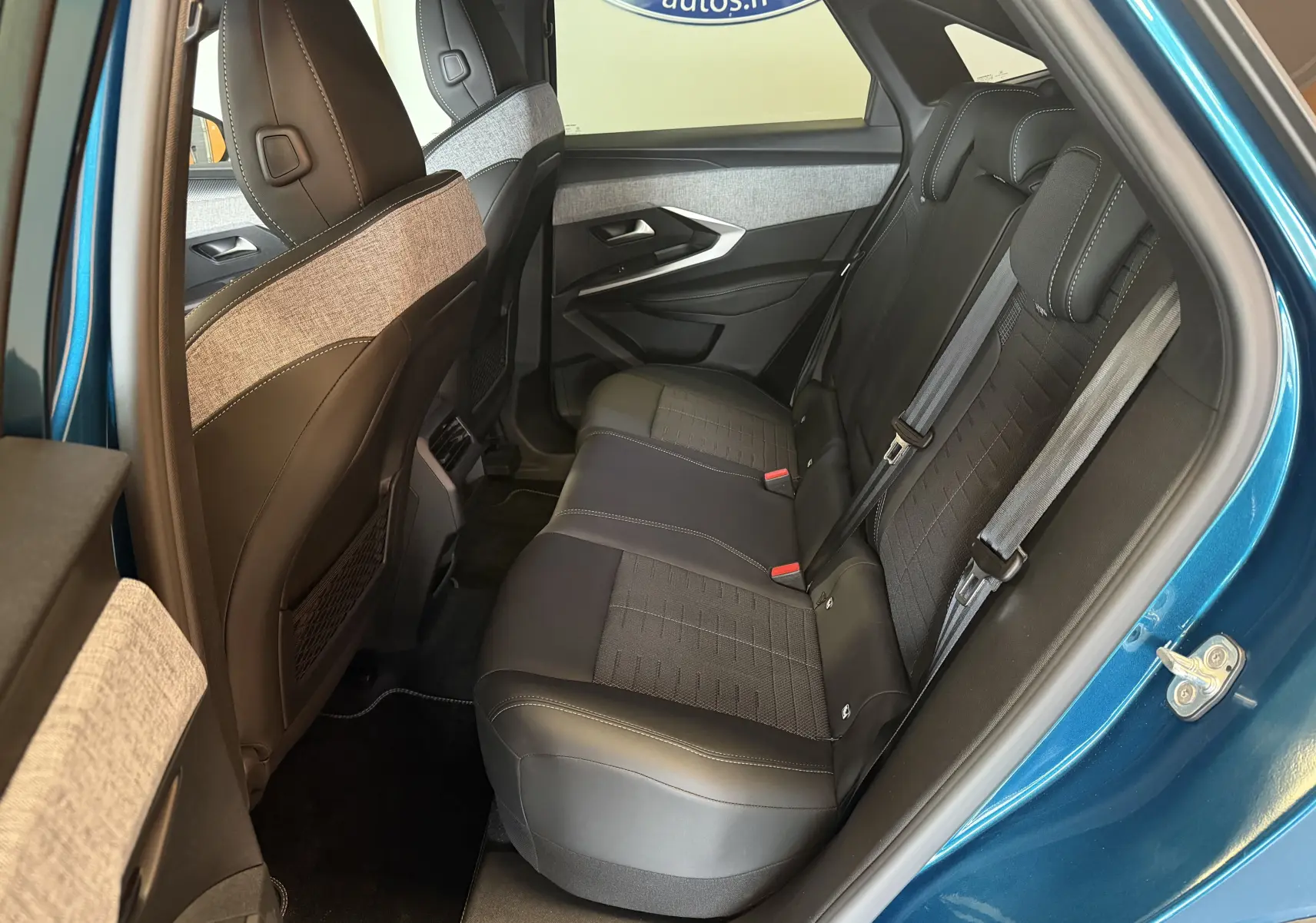 Vue intérieure côté gauche des sièges arrière du Peugeot 3008 Hybrid 145 GT bleu Obsession avec sellerie tissu embossé et surpiqûres claires.