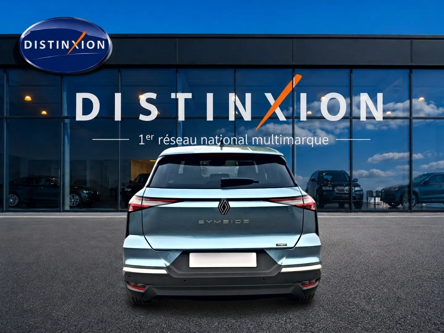 Vue arrière d'une Renault Symbioz bleu mercure avec feux LED et logo centré devant une vitrine Distinxion.