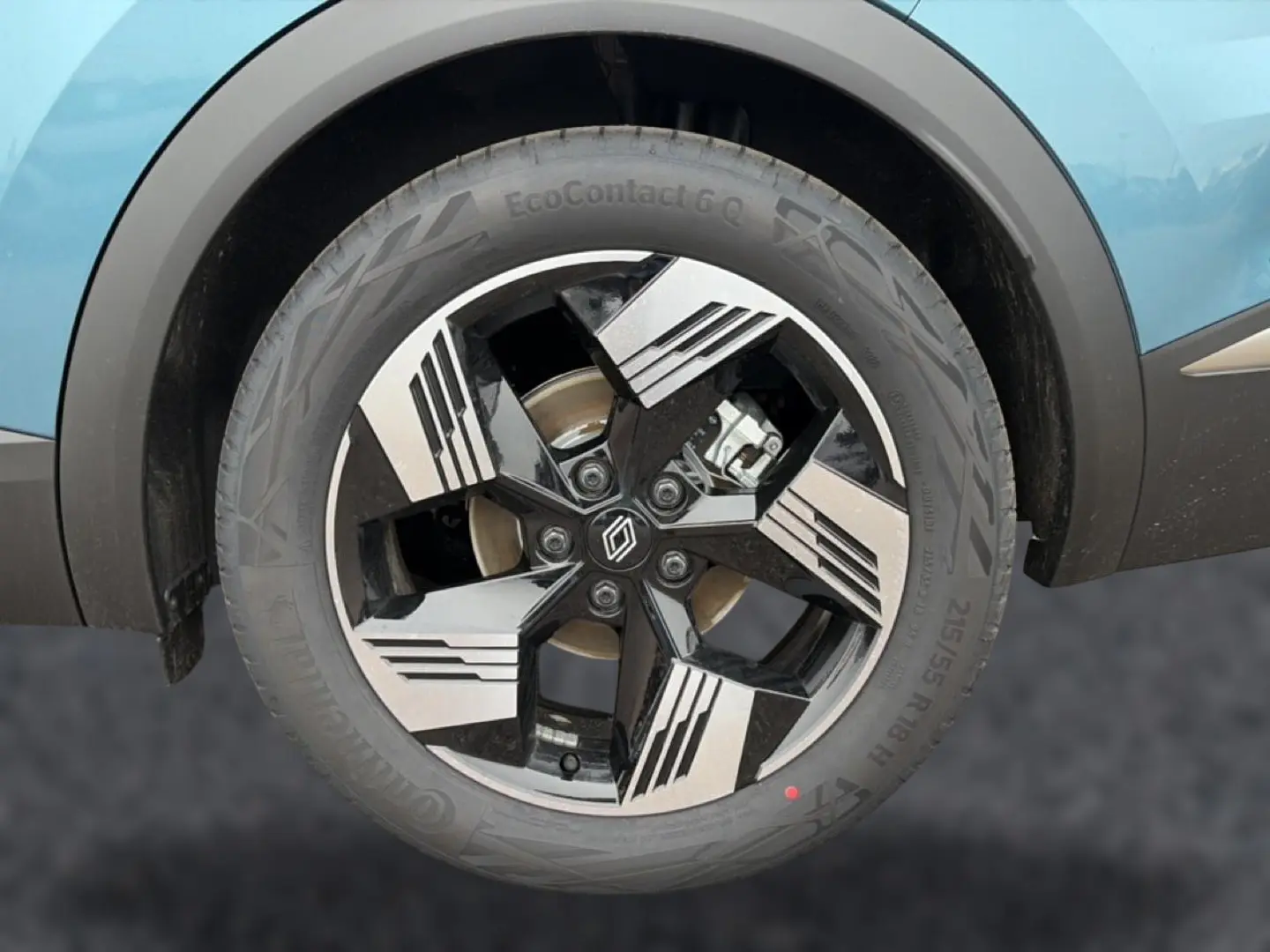 Gros plan sur la roue avant droite du Renault Symbioz bleu mercure, avec jante alliage noire et argent au design géométrique.